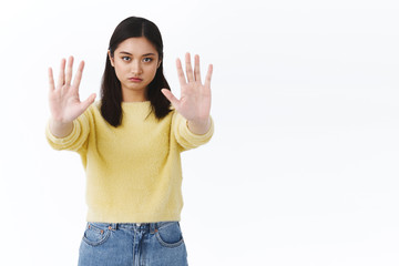 Stop right there. Serious-looking asian girl pulling hands forward in prohibition, disagree...