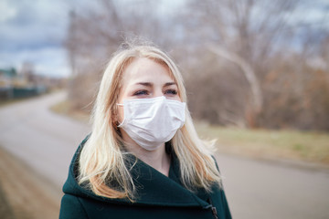 blonde girl in a medical mask on the street