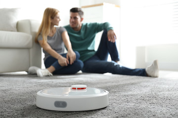 Couple spending time together while robotic vacuum cleaner doing its work at home