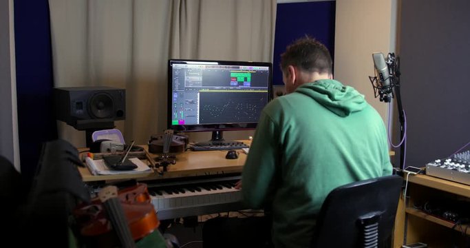 Musician recording keyboard / synth / piano in recording studio onto a DAW (Digital Audio Workstation). A home recording studio setup ideal for singer songwriters creating new music.