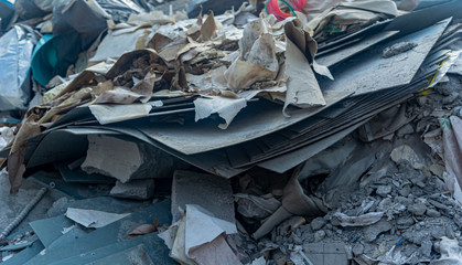construction debris, sheets of asbestos, paper, bricks closeup