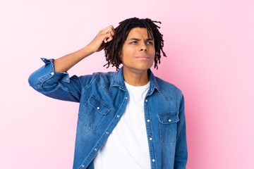 Young African American man with jean shirt over isolated pink background having doubts and with...