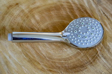 Round shower head made of metallic color plastic on a natural wood background