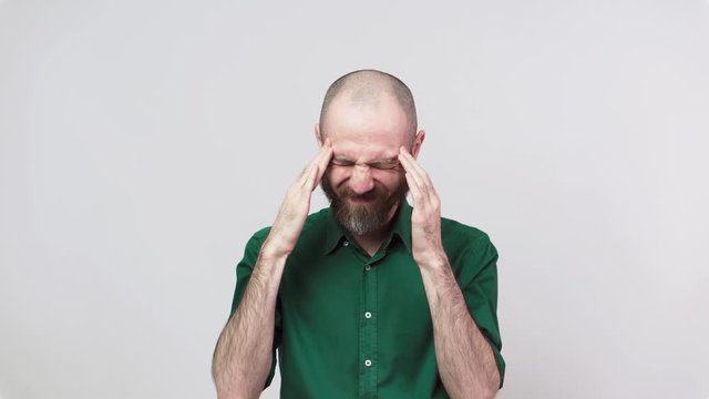 Portrait of bearded man having headache isolated over white background. Sick unhappy man rubbing temples. Concept of emotions.