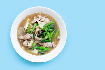 Fried noodle with pork  and chinese broccol, cauliflower in white dish on blue background.