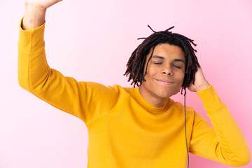 Young African American man listening music over isolated pink wall