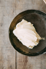 A piece of butter in a dark dish. Melted vegetable oil for cooking.