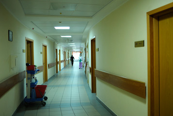 Corridor of a hospital, blurred nurse in the face mask and lab coat standing at the end