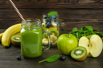 healthy green smoothie with spinach in glass and fruits