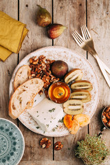 Flatley cheese plate with figs. Snacks for the company. Set of cheeses on a plate with honey and nuts.