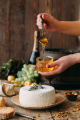  A large white round cheese on a plate. Curd cheese is watered with honey. The chef's hands prepare cheese.