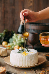  A large white round cheese on a plate. Curd cheese is watered with honey. The chef's hands prepare cheese.