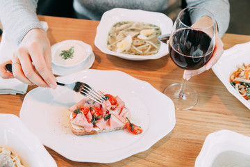 Restaurant dish on the menu with wine. The girl is eating bruschetta with bacon and tomato.