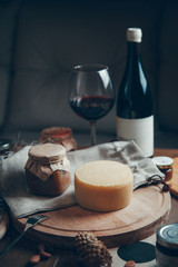 A smooth circle of hard cheese with wine and a glass. Farm cheeses on a wooden Board. Still life with hard sliced cheese.