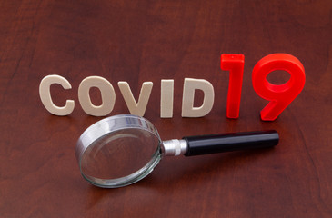 Information about coronavirus covid-19 theme. Magnifying glass and word covid19 on table.