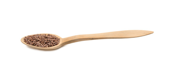 Low angle side view of linseed or flax seeds on a wood spoon and isolated on white background