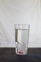 Pink fresh multi vitamin and mineral effervescent tablet dissolving in tall glass of water