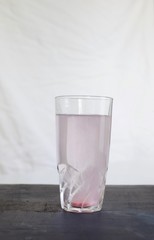Pink fresh multi vitamin and mineral effervescent tablet dissolving in tall glass of water