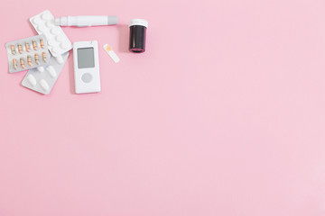 glucometer and pills on  pink background