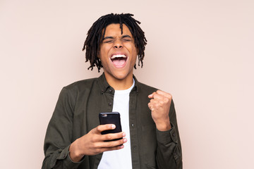 Young African American man over isolated background with phone in victory position