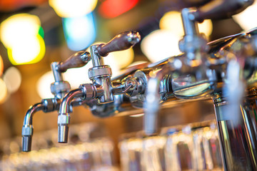 glass of beer in pub, hand of bartender pouring a large lager beer in tap, the beer taps in a pub