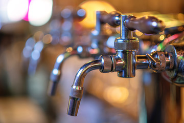 glass of beer in pub, hand of bartender pouring a large lager beer in tap, the beer taps in a pub