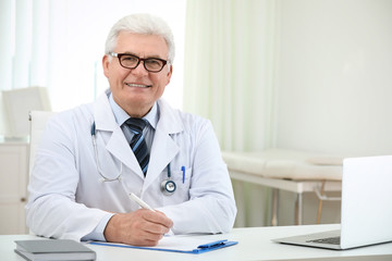 Portrait of senior doctor in white coat at workplace