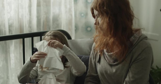 Mama opiekuje się chorą dziewczynką, kt&oacute;ra ma katar i leży w ł&oacute;żku.