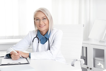 Portrait of mature female doctor in white coat at workplace