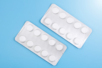 Blister with white tablets is isolated on a blue background. The concept of medicine, drugs, painkillers. Copy space