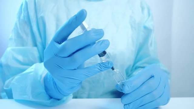 Vaccination injection. Healthcare service. Doctor hands in gloves filling syringe from ampoule.