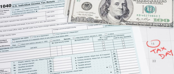 US 1040 tax return form with 100 usd dollar bills and calendar