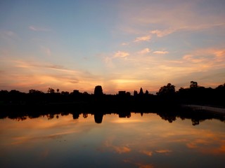 Angkor Wat during sunrise with pink clouds, shadows before lake with reflections, ruins of Angkor, Cambodia