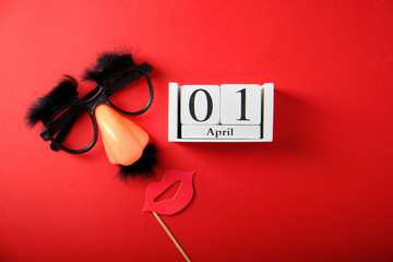 False glasses, nose and mustache for April 1, April Fool's Day, on a red background, wooden calendar