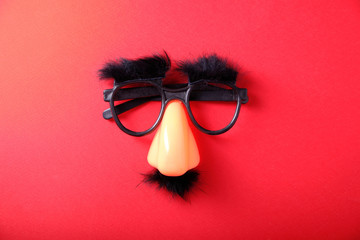 Overhead glasses, nose and mustache for April 1, April Fool's Day, on red background - obrazy, fototapety, plakaty
