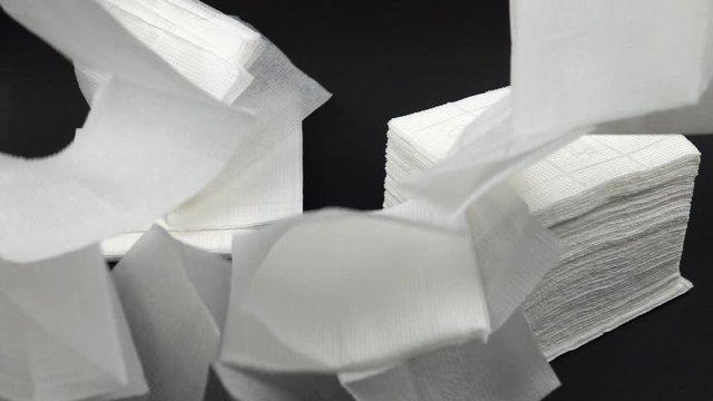 White paper napkins fall on black table,  slow motion
