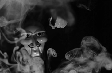 White scary mask on a black background with whites hand.