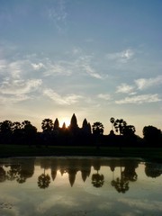 Naklejka premium Angkor Wat during sunrise with clouds, shadow Silhouette before lake with reflections, ruins of Angkor, Cambodia