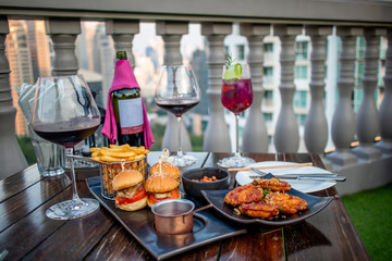 The red vine in the glasses served with burgers and fried chicken on the wooden table next to the balcony i nthe restaurant.