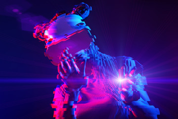 Woman is using virtual reality headset. Neon light studio portrait. Image with glitch effect.