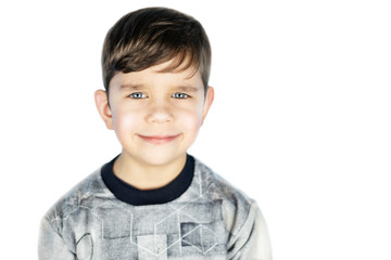 Portrait of young boy with innocent smile on a white background, isolated. It is seen that the boy is very kind and gentle