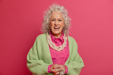 Disappointed indignant grey haired senior woman looks puzzled, smirks face, has white perfect...