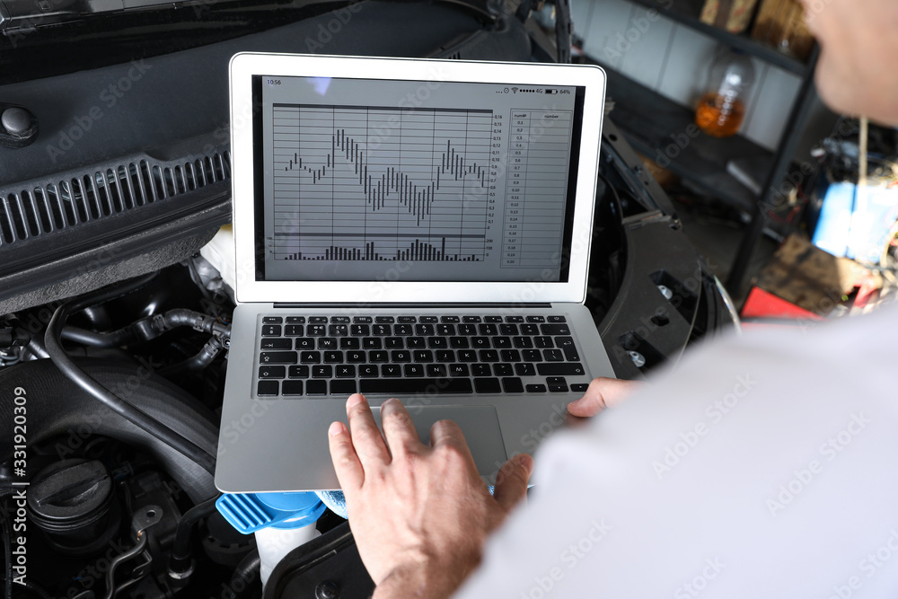 Canvas Prints Mechanic with laptop doing car diagnostic at automobile repair shop, closeup