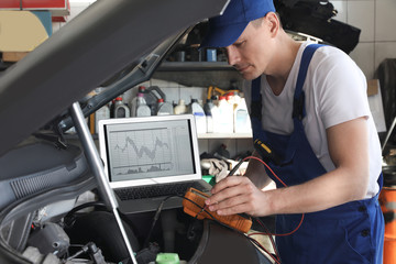 Mechanic with laptop doing car diagnostic at automobile repair shop