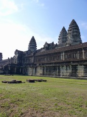 Stone building of Angkor Wat with green grass before blue sky, ruins of Angkor, Cambodia