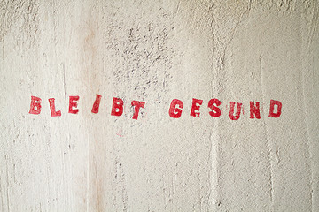 Bleibt Gesund, Schriftzug zu Corona in rot auf weisser Wand