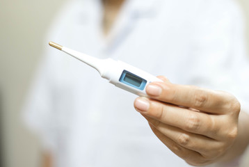 Woman hand holds analogue medical thermometer to  measure the body temperature, protection from virus