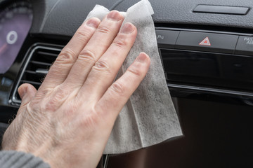 Man cleaning front dashboard of a car using antivirus antibacterial wet wipe (napkin) for protect himself from bacteria and virus.