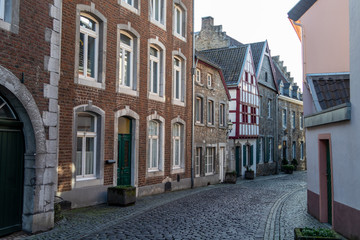 Fototapeta na wymiar Narrow road with cobblestone pavement and historic buildings in Stolberg, Eifel