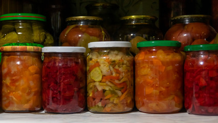 Fototapeta na wymiar Pantry shelf with provisions in glass jars with pickled vegetables
